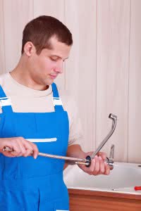 Plumber fitting a tap on a kitchen sink