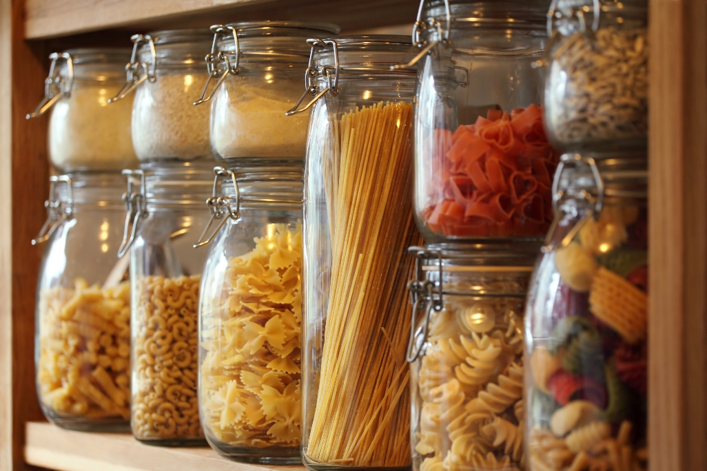 dried pasta in jars on a shelf in a domestic kitchen. Very shallow depth of field focusing on the middle jar.